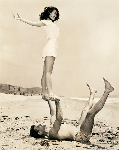 Ava Gardner balancing on a man’s feet on a beach